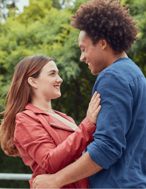 A smiling couple holding each other A smiling couple holding each other with trees in the background